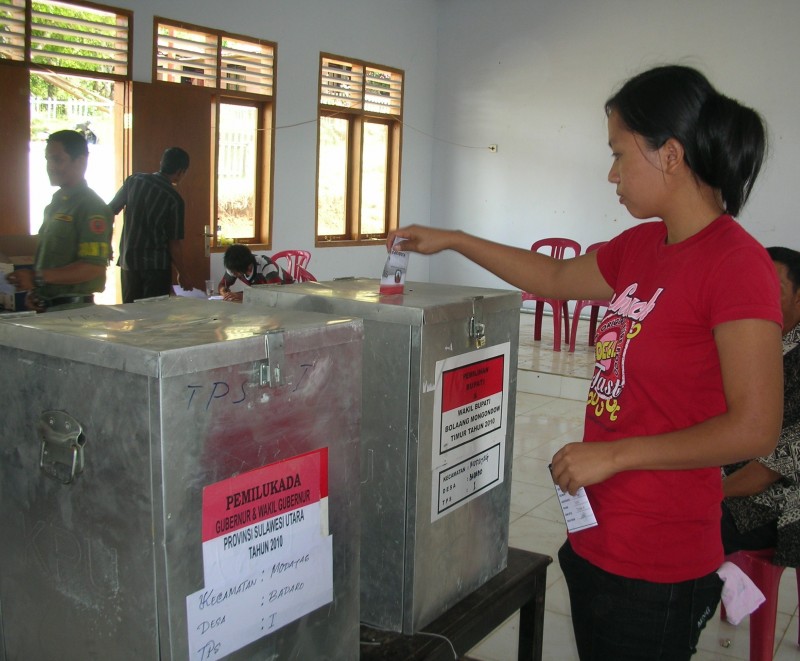 Seorang pemilih memasukan kertas ke kotak suara dalam pemilihan kepala daerah di Sulawesi Utara. (Foto: Kandi)